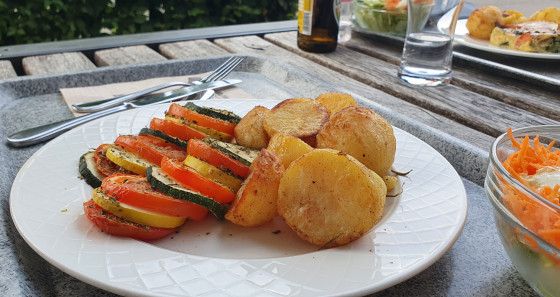 Ein kühles Getränk sowie ein Tomaten-Zucchini Auflauf mit Salat und Rosmarinkartoffeln halfen bei der Entspannung auf der Terrasse mit Blick auf den See. 